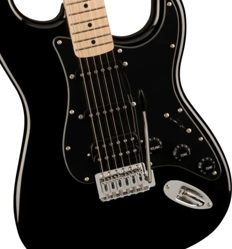 Close-up of a black electric guitar body with strings and controls.