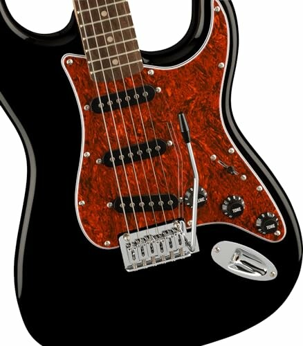 Black electric guitar from the back with a red pickguard and three pickups